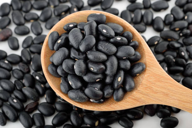 istock Close up black beans in a wooden spoon 1303251694
