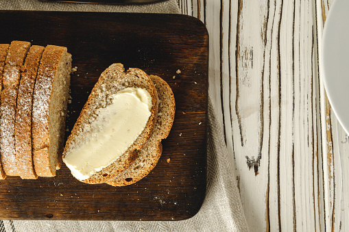 Buttered slice of rye bread on wooden table background