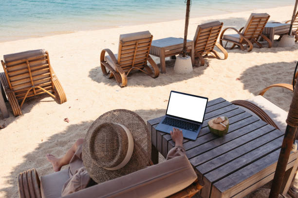 istock a woman using and touching on laptop touchpad with blank desktop screen while sitting on the beach 1303255463