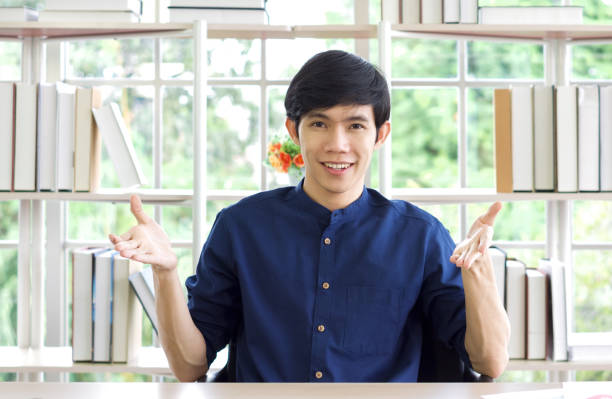 istock Smiling asian man looking at camera, recording self-presentation video or sharing professional skills. Happy young smart people filming educational lecture. 1303256597