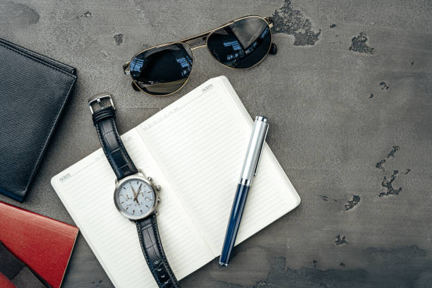istock Businessman's accessories including notepad, watch and purse on dark grey background 1303257403