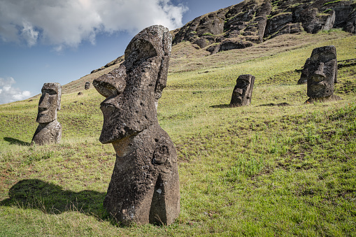 Moai Statues on Easter Island. Rapa Nui Moai Statues at Rano Raraku hills under sunny summer cloudscape. Rano Raraku is a volcanic crater formed of consolidated volcanic ash. Terevaka, Rano Raraku, Rapa Nui National Park, Hanga Roa, Easter Island - Isla de Pascua, Chile, Oceania