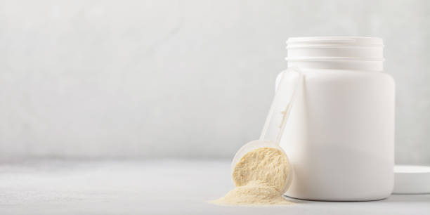 proteine del siero di latte in polvere in misurino e barattolo su sfondo grigio. - bevanda proteica foto e immagini stock