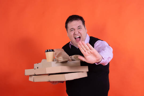 istock Diet and funny t man. The guy is eating a small pizza. 1303263582