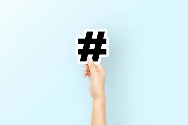 Hand holding paper with icon hashtag on light blue background