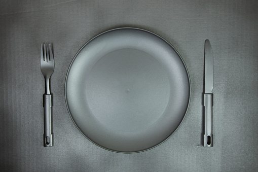 gray plate and cutlery on metallic gray background