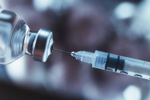 istock Syringe draws vaccine from ampoule. Coronavirus and flu cure. Close-up view. 1303284098