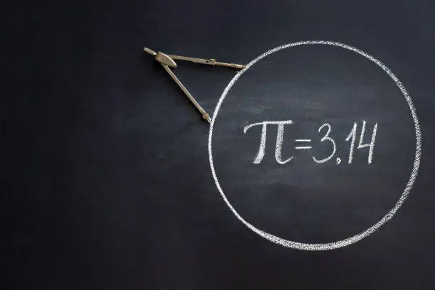 Photo of The Greek letter Pi, the ratio of the circumference of a circle to its diameter, is drawn in chalk on a black chalkboard with a compass in honor