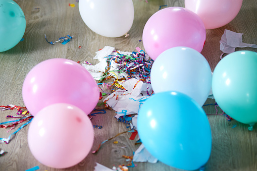 The mess after the birthday celebration with balloons and confetti on the floor, After party chaos, Messy room.