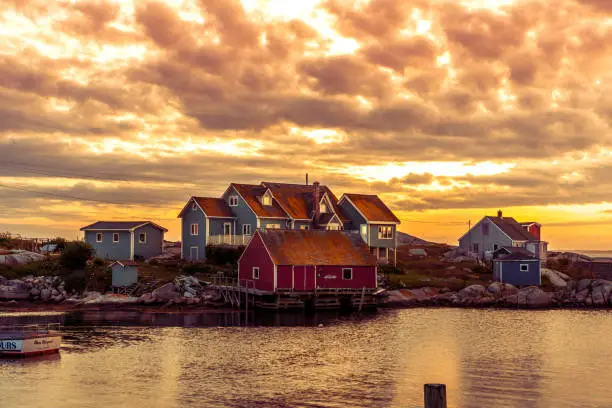 Peggy's Cove - small fishing village on the Atlantic coastline of Nova Scotia, Canada. View of traditional wooden fisherman houses against sunset sky