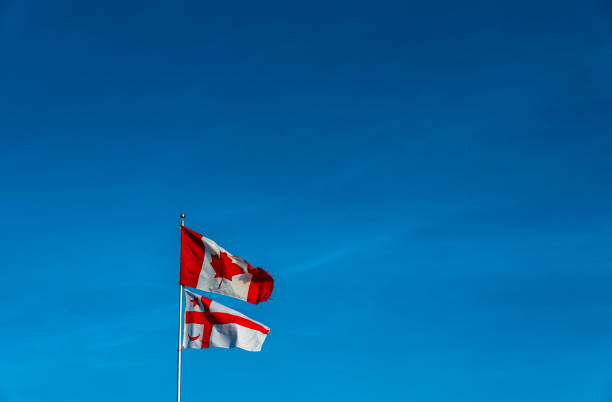 istock Mi'kmaq State flag flying on a pole with Canadian flag against blue sky 1303291481