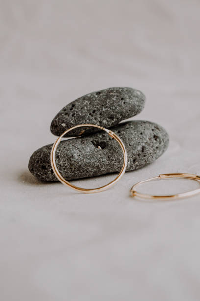 Golden hoop earrings minimal styled with stones and earthy tones. Earrings Close up view. Selective focus Golden hoop earrings minimal styled with stones and earthy tones. Earrings Close up view. hoop earring stock pictures, royalty-free photos & images