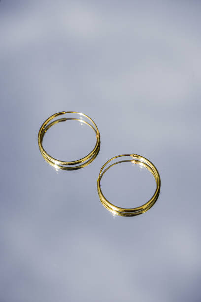 Golden hoop earrings with the sky on the background. Selective focus. Jewels background Golden hoop earrings with the sky on the background. Selective focus. hoop earring stock pictures, royalty-free photos & images