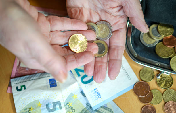 Close-up: Elderly woman counts small change in her hand, Euro bills and a wallet are on the table Elderly woman counts small change in her hand, bills are on the table - selective focus, high angle view money shortage stock pictures, royalty-free photos & images