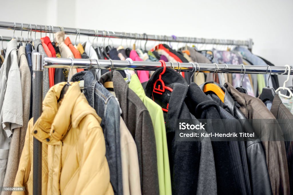 Different used clothes for men and women on a rack in a second hand shop or thrift store Second hand or poverty concept: Different used clothes for men and women on a rack in a second hand shop or thrift store - selective focus with little depth of field Charitable Donation Stock Photo