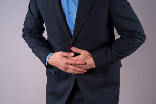 istock Office worker with abdominal pain, stomach ache on gray background 1303293112