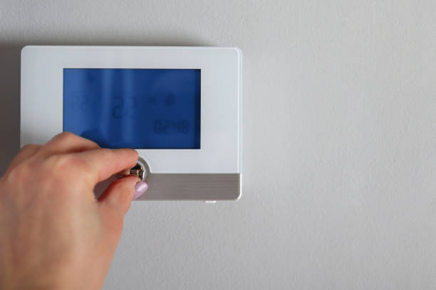 istock Woman hand pushing button on thermostat device with digital display at home 1303294407