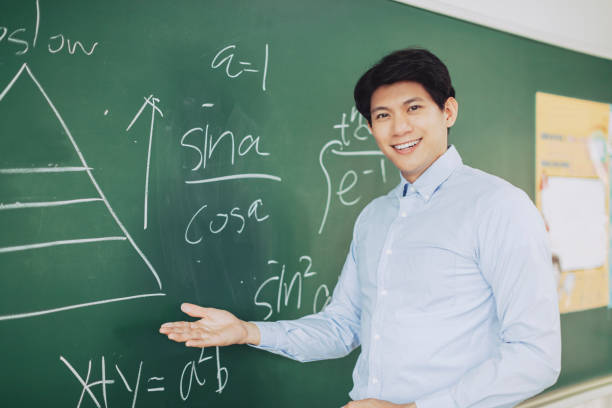 istock young smiling teacher standing in front of chalkboard 1303295184