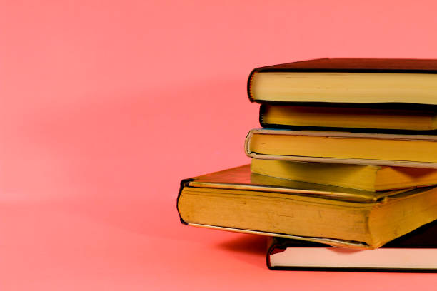 istock Stacked books on pink background 1303295772