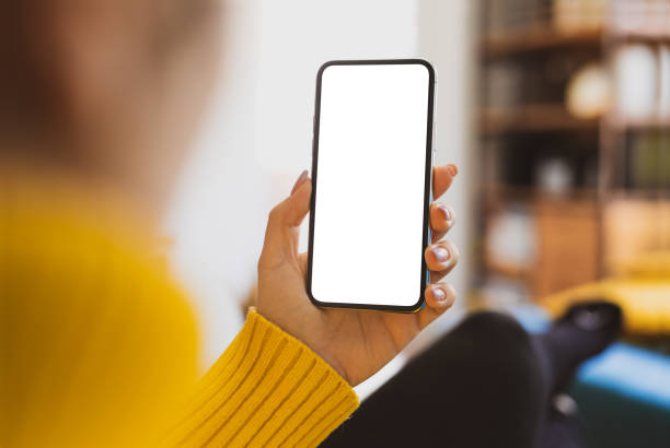 istock Woman using smartphone frameless mockup blank screen in home interior. Working from home concept - video calling 1303296551