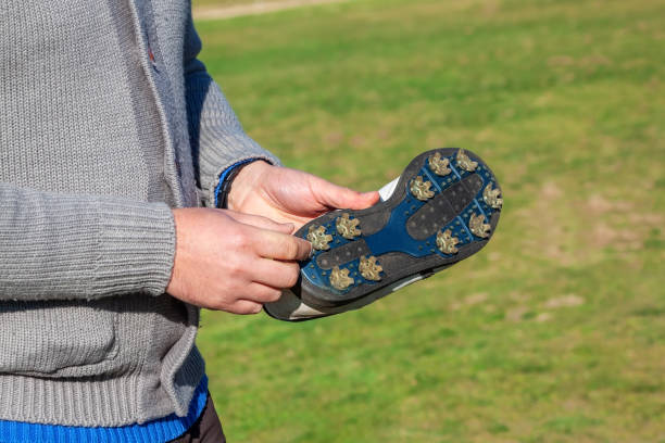 feche acima de um golfista mostrando um sapato de golfe com espinhos para ajudar a aderir ao campo de grama. calçado de golfe. - calçado com pitões - fotografias e filmes do acervo