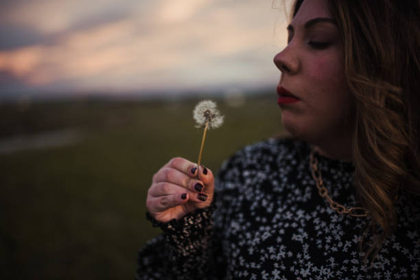 istock Young woman blowing a dandelion 1303299245