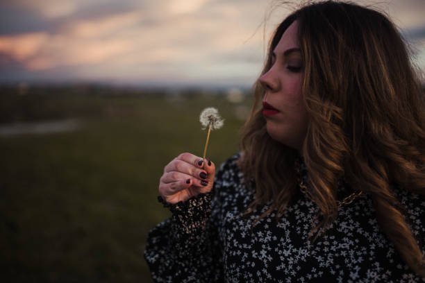 istock Young woman blowing a dandelion 1303299277