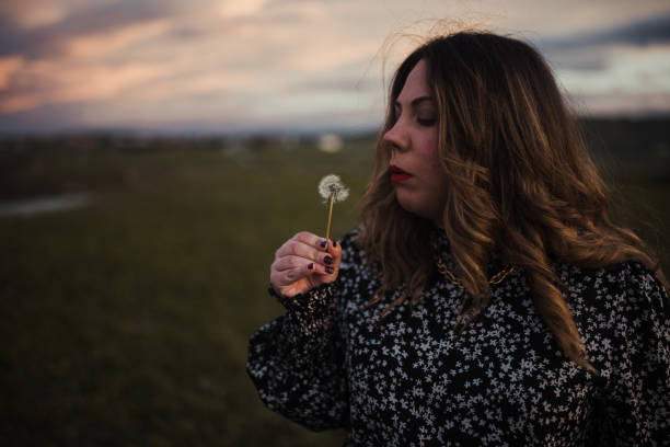istock Young woman blowing a dandelion 1303299325