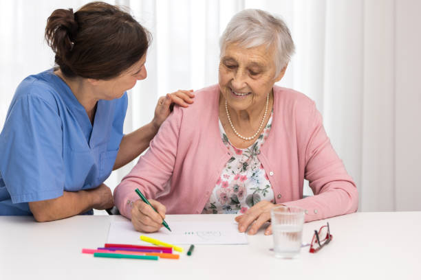 istock Nursing home therapy- senior woman drawing on white paper 1303301265
