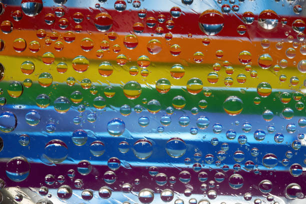 istock Rainbow. Multicolored drops of water are located against a blue background with strips of rainbow colored paper. 1303301351