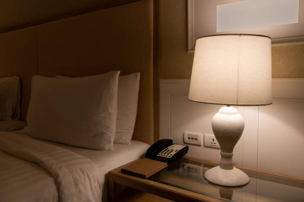 istock Lamp on a night table next to classic bed 1303301668