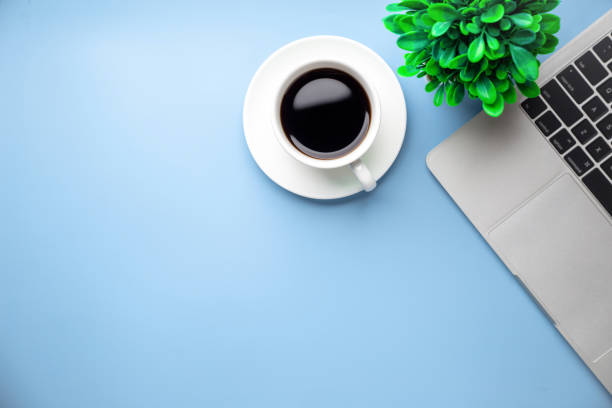 istock Flat lay, top view office table desk. Workspace with, laptop,office supplies, pencil, green leaf, and coffee cup on blue background. 1303304652