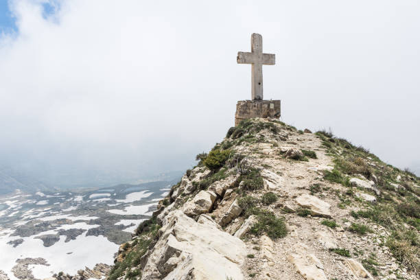 Cross on a cliff overlooking a valley on a cloudy day in Sayidat al Qarn church, Aaqoura, Lebanon