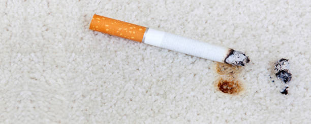 istock Smoldering cigarette on carpet with burn hole banner 1303305866