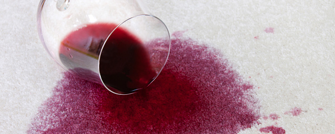 Overturned wine glass with red wine on carpet