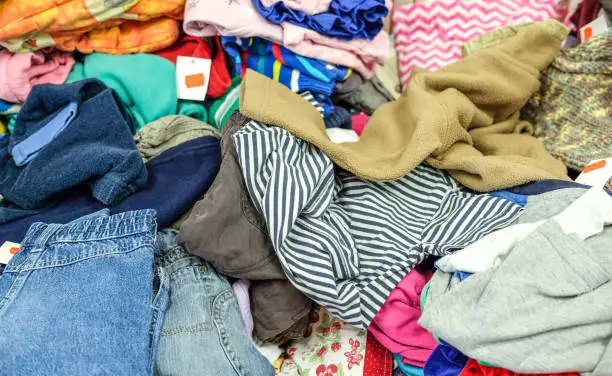 High angle view on different kinds of used clothes for children and babies in a second hand shop - selective focus