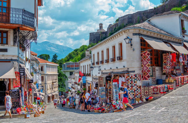 Summer cityscape of Gjirokaster town, Albania Gjirokaster town, Albania –August 2, 2020: summer cityscape – street of ancient town with souvenir shops and tourists. Old historical architecture and Castle complex on the hill. albania photos stock pictures, royalty-free photos & images