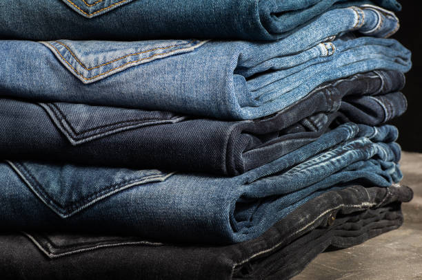 istock Stack of various denim jeans, trousers on stone rustic background, fashion design 1303307217