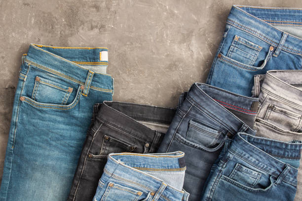 istock Stack of various denim jeans, trousers on stone rustic background, fashion design 1303307878