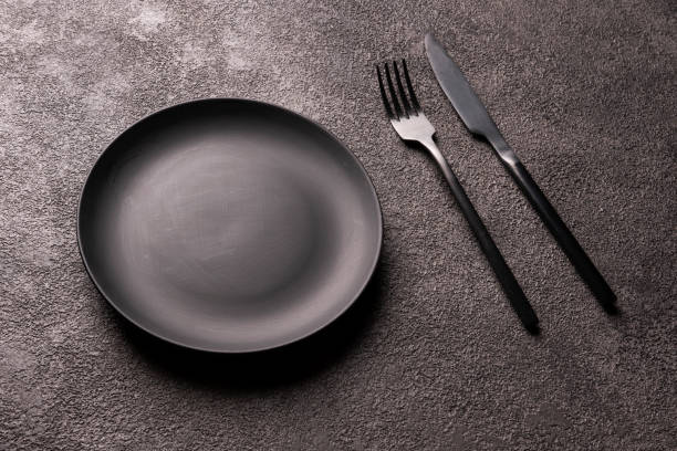 istock an empty black plate, fork and spoon on a dark background. minimalistic still life 1303308996