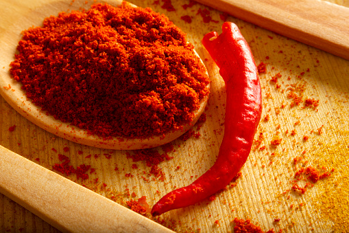 Red powder pepper in wooden spoon, studio shot
