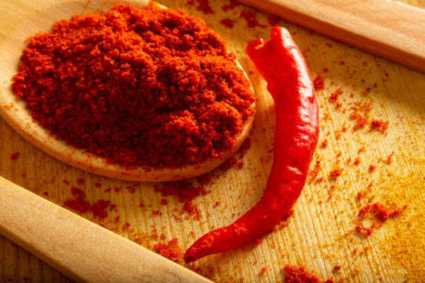 Red powder pepper in wooden spoon, studio shot stock photo