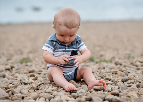 Small boy playing with stones on the seaside