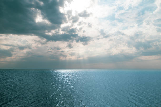 istock blue sea and cloudy sky over it. Blue Sea sky and Clouds with sun behind 1303314301