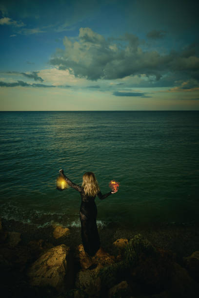istock Woman with glowing lantern at the sea 1303318745