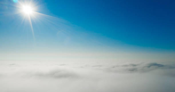 istock Sun rays shining in the blue sky above white and fluffy clouds 1303319727