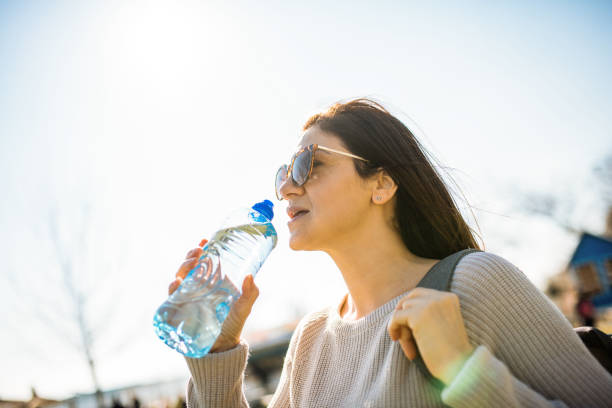 istock Woman drinking water from plastic bottle outdoors, low angle view 1303319748