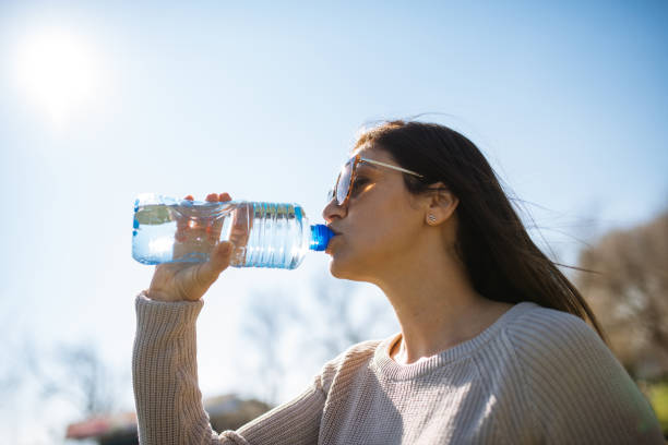istock Woman drinking water from plastic bottle outdoors, low angle view 1303319983