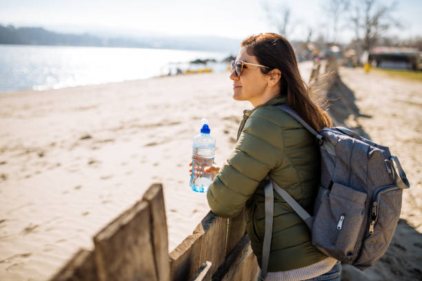 istock Woman drinking water from plastic bottle outdoors and enjoying the view 1303320037