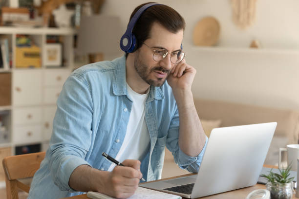 istock Young man getting remote education sitting by laptop in headphones 1303320166